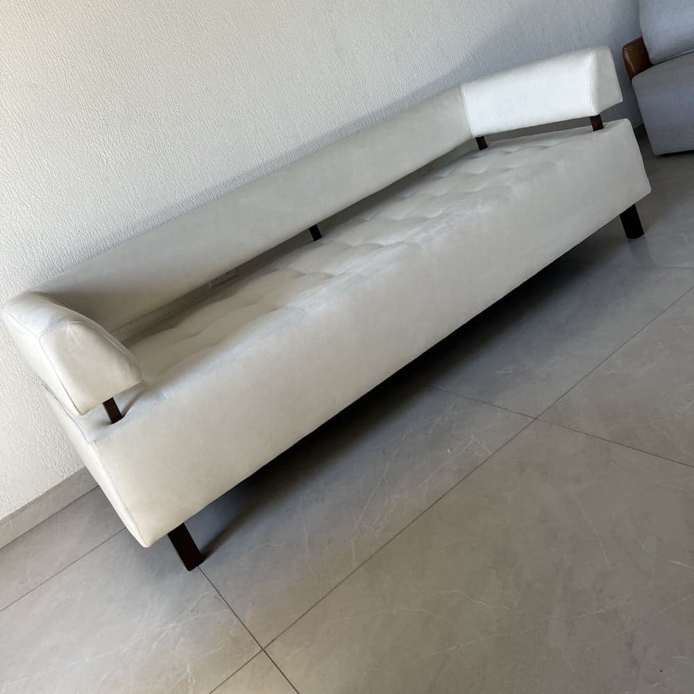 Sofá reformado com assento capitonê e encosto elevado sobre porcelanato cinza